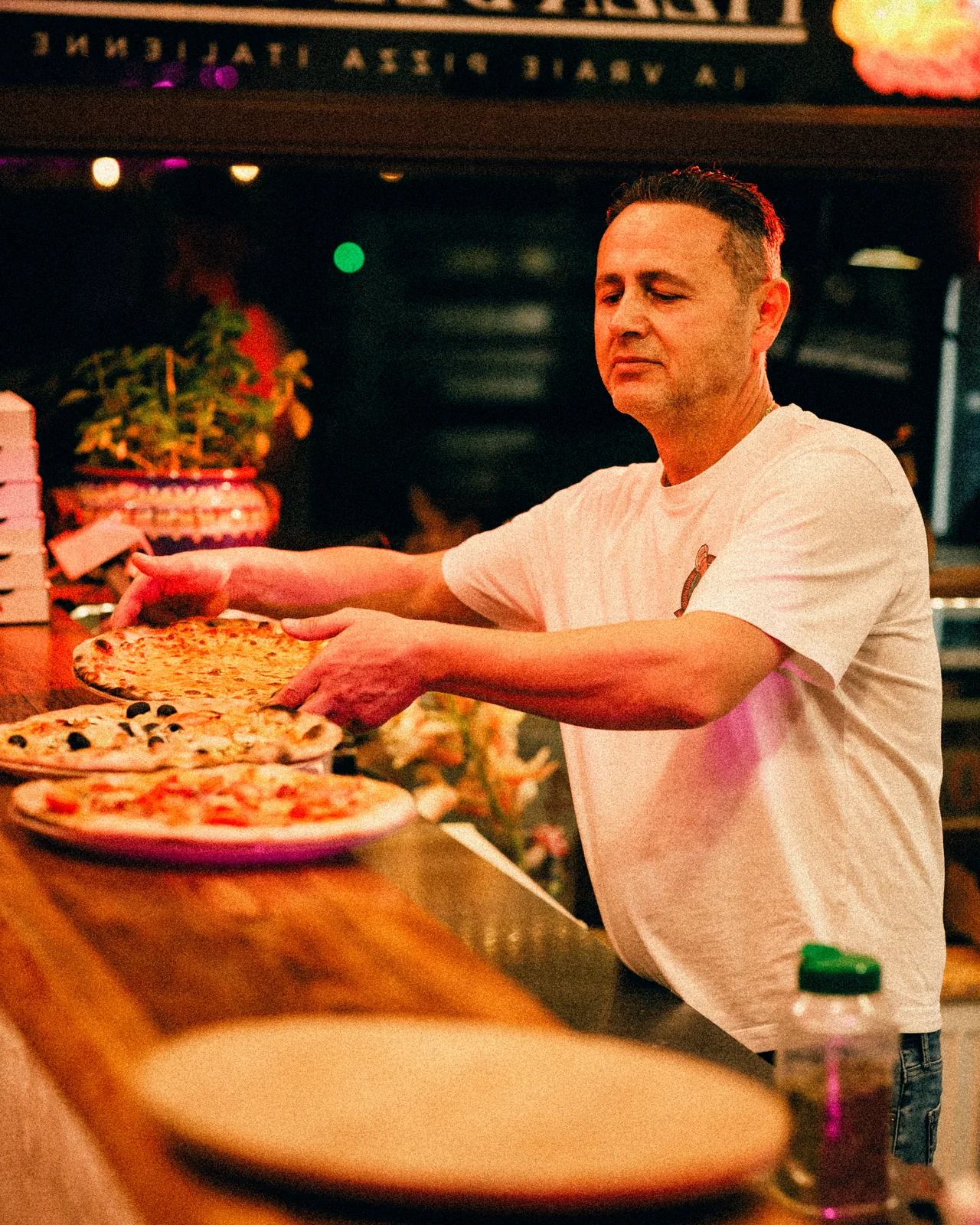 Le patron pose les pizzas sur le comptoir