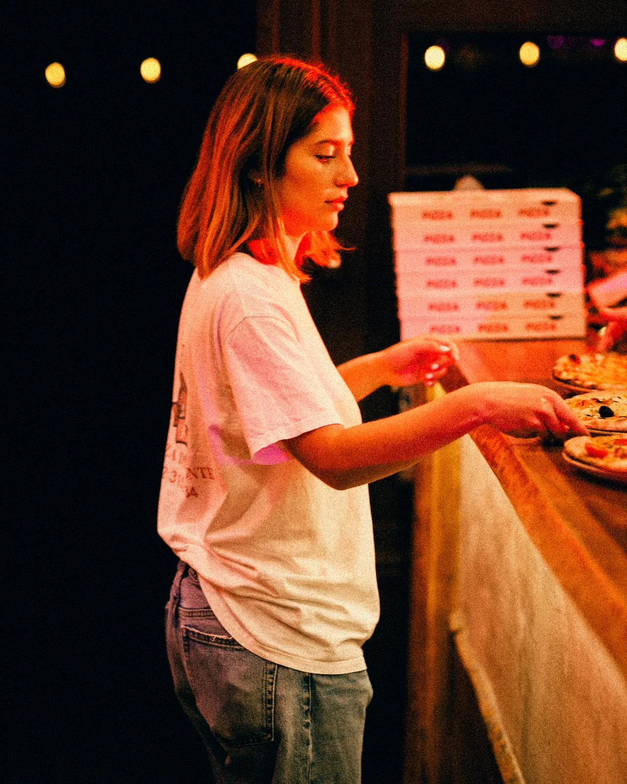 Une serveuse prend les pizzas au comptoir