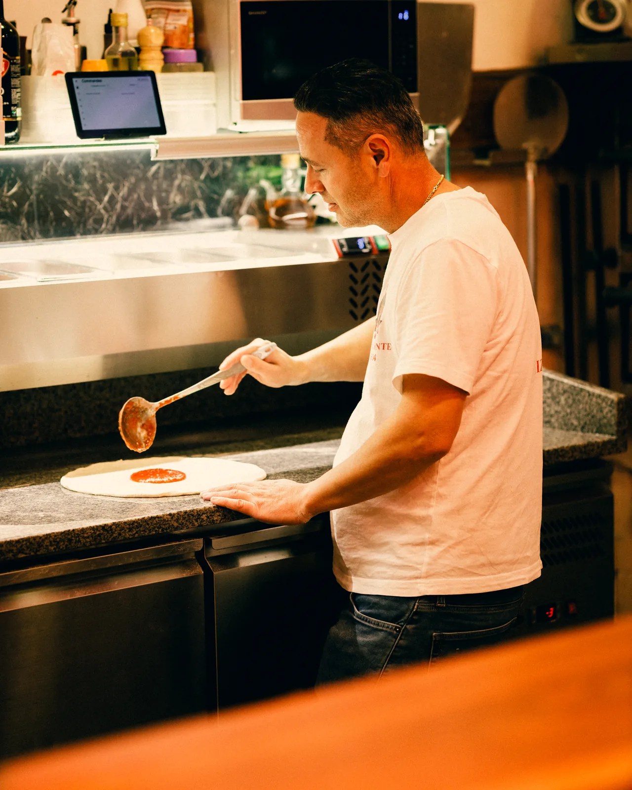 Le pizzaiolo étale la sauce tomate sur la pâte